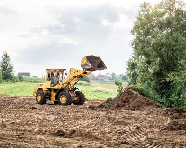 large yellow wheel loader aligns a piece of land for a new building